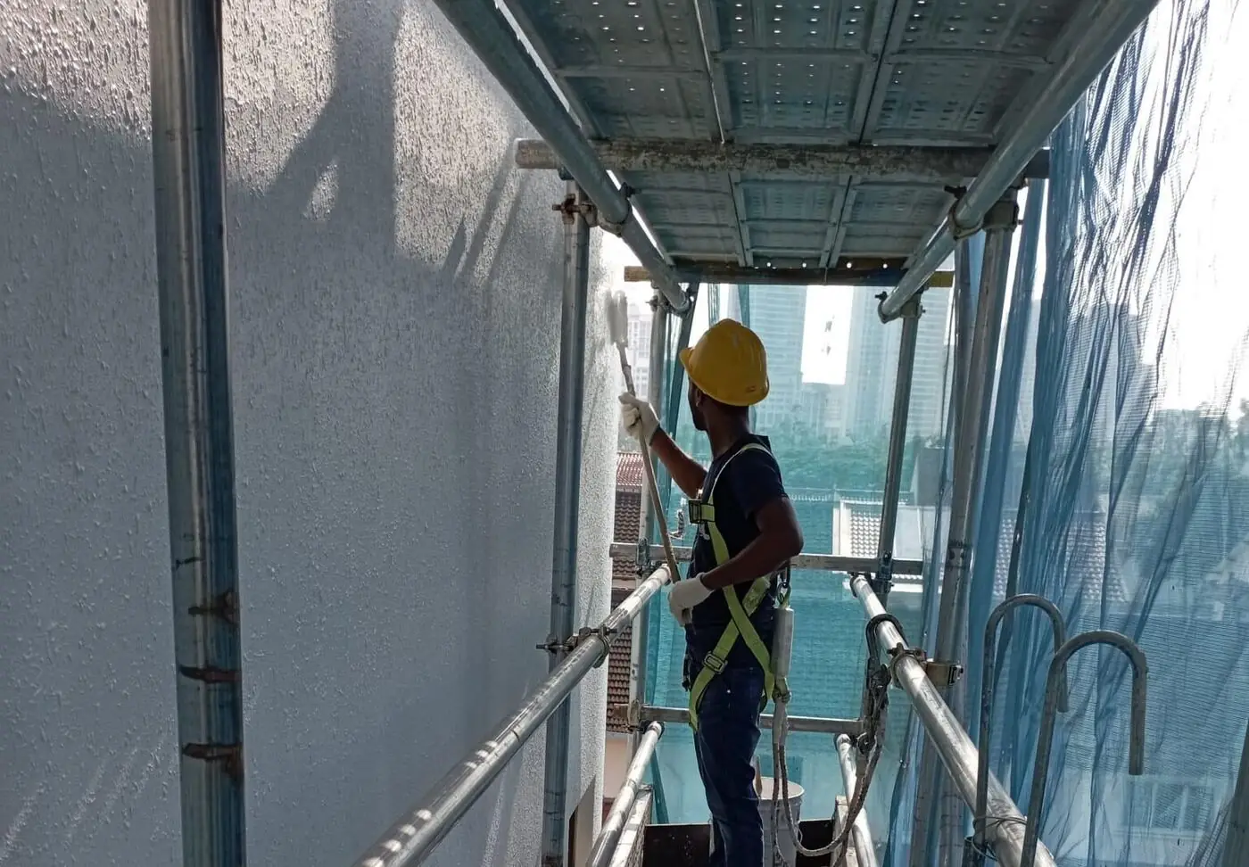 Technician carrying out external façade painting and sealant repair in Singapore