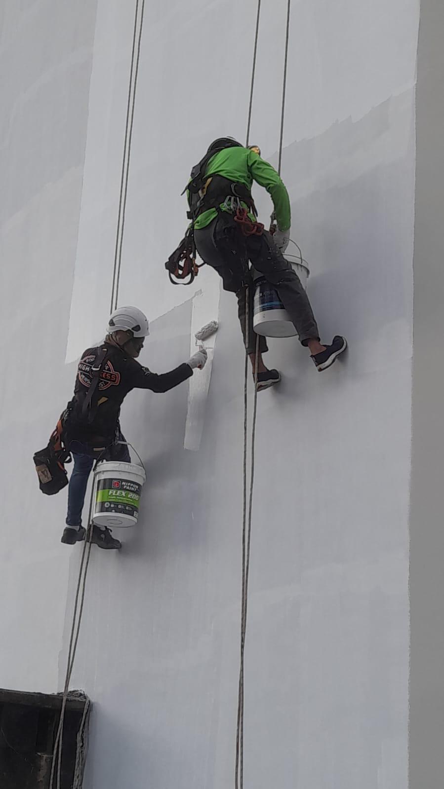 Rope access technician on a high-rise residential facade carrying out waterproofing repair as part of a multi-bay programme