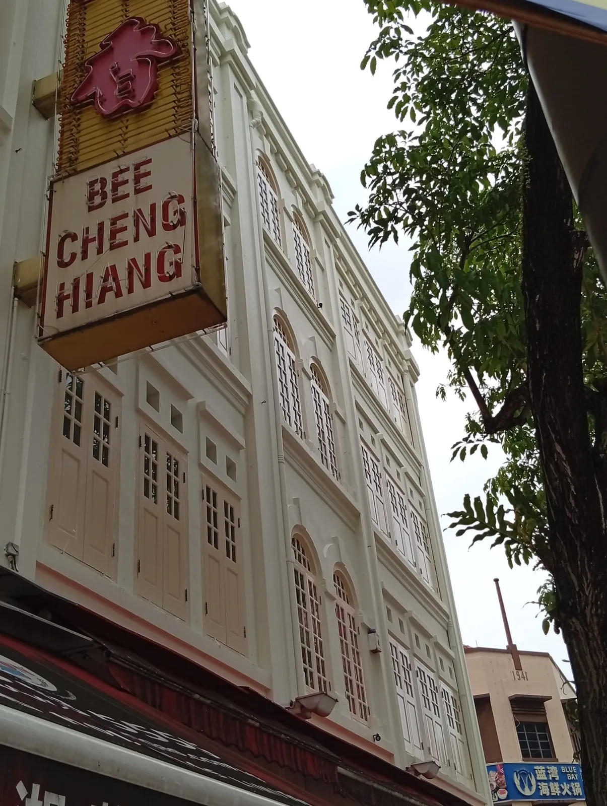 Bee Cheng Hiang sign on the restored upper façade with arched windows and shutters