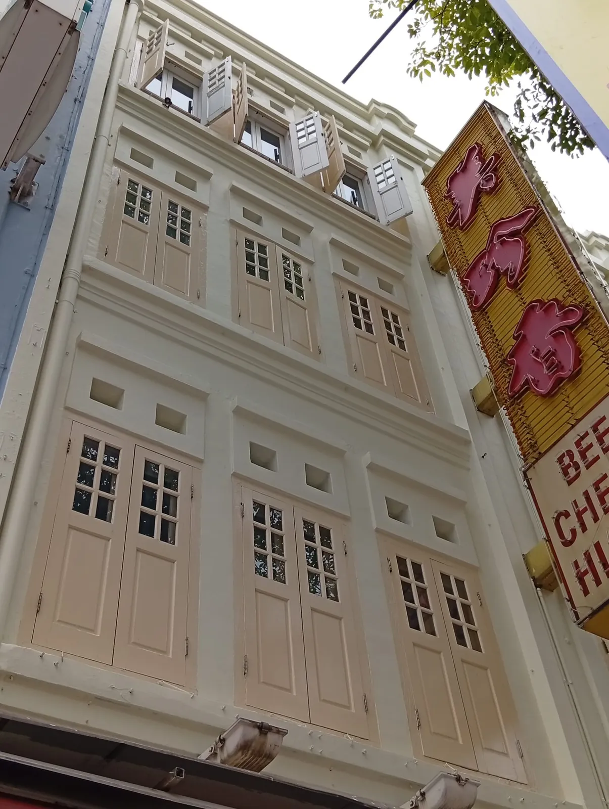 Repainted upper façade with mouldings and refinished timber shutters, seen from street level