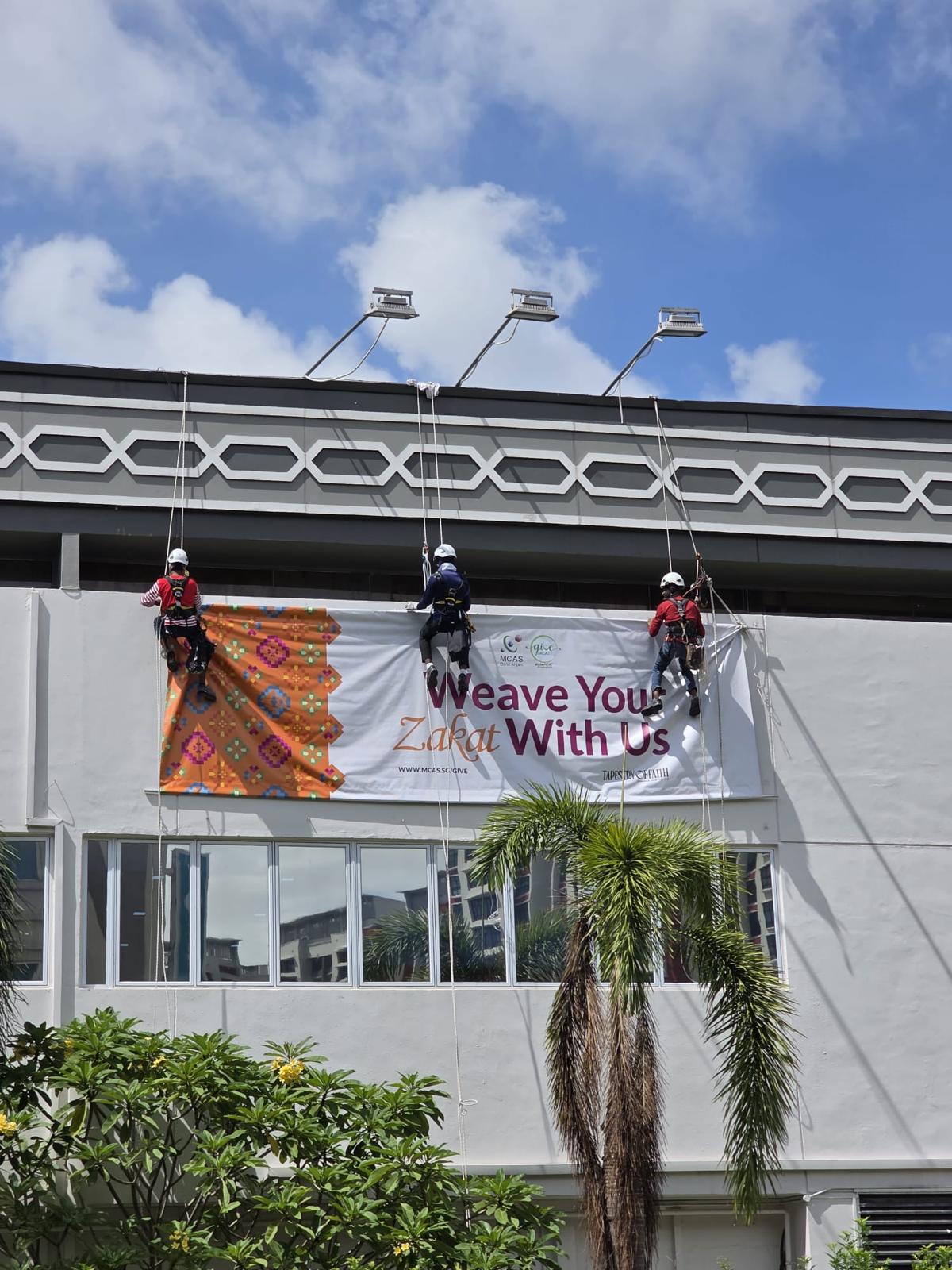 Wider elevation view of the MCAS Darul Arqam building during the Zakat campaign banner replacement programme