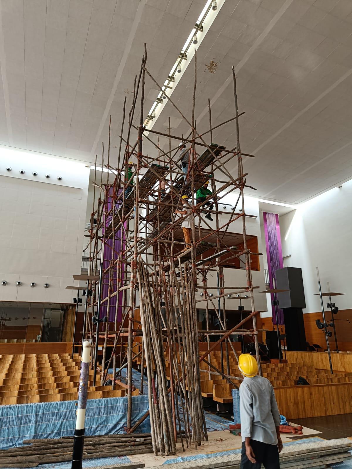 Full 12-metre timber scaffold tower wrapped in green debris netting inside the church nave reaching the high-level ceiling for board replacement