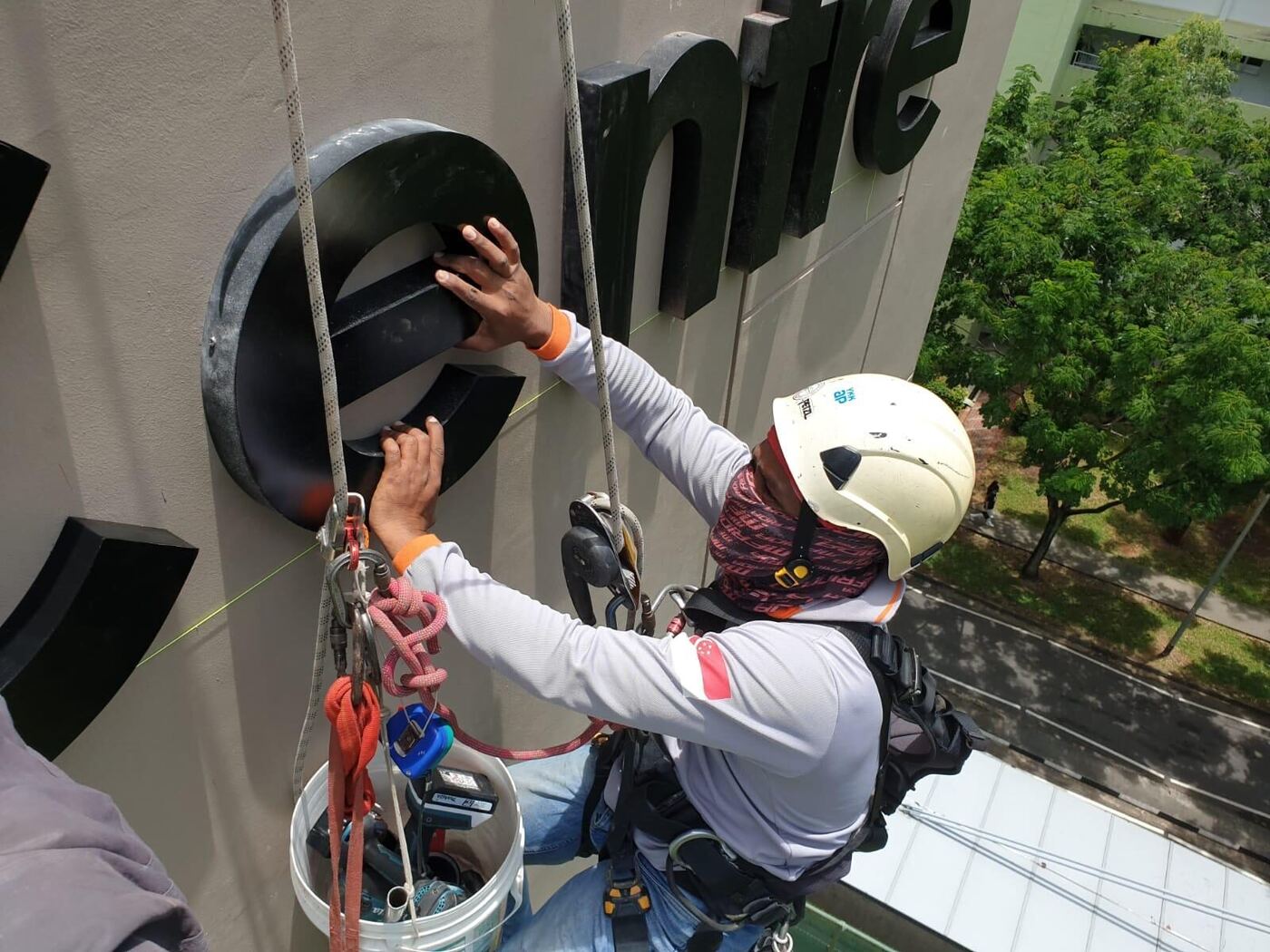 Boomlift positioned next to a building façade for high-level signage work in Singapore